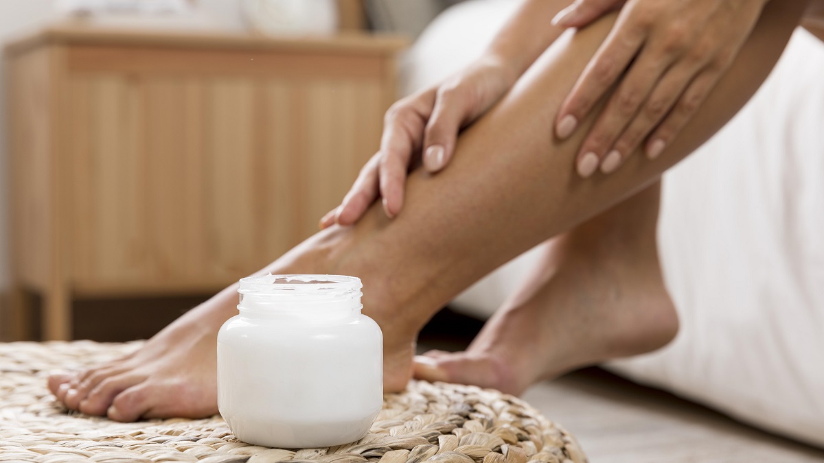 Femme appliquant de la crème sur ses jambes.