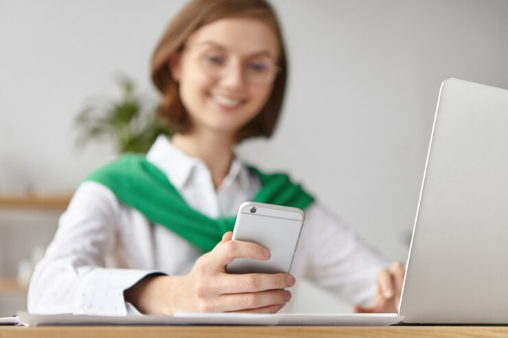 Femme connectée sur son smartphone et ordinateur.